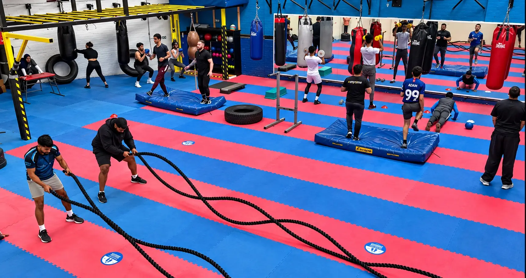 A Cardiobox circuit in progress, with battle ropes, plyo boxes, dumbbells and mats in use across the gym floor