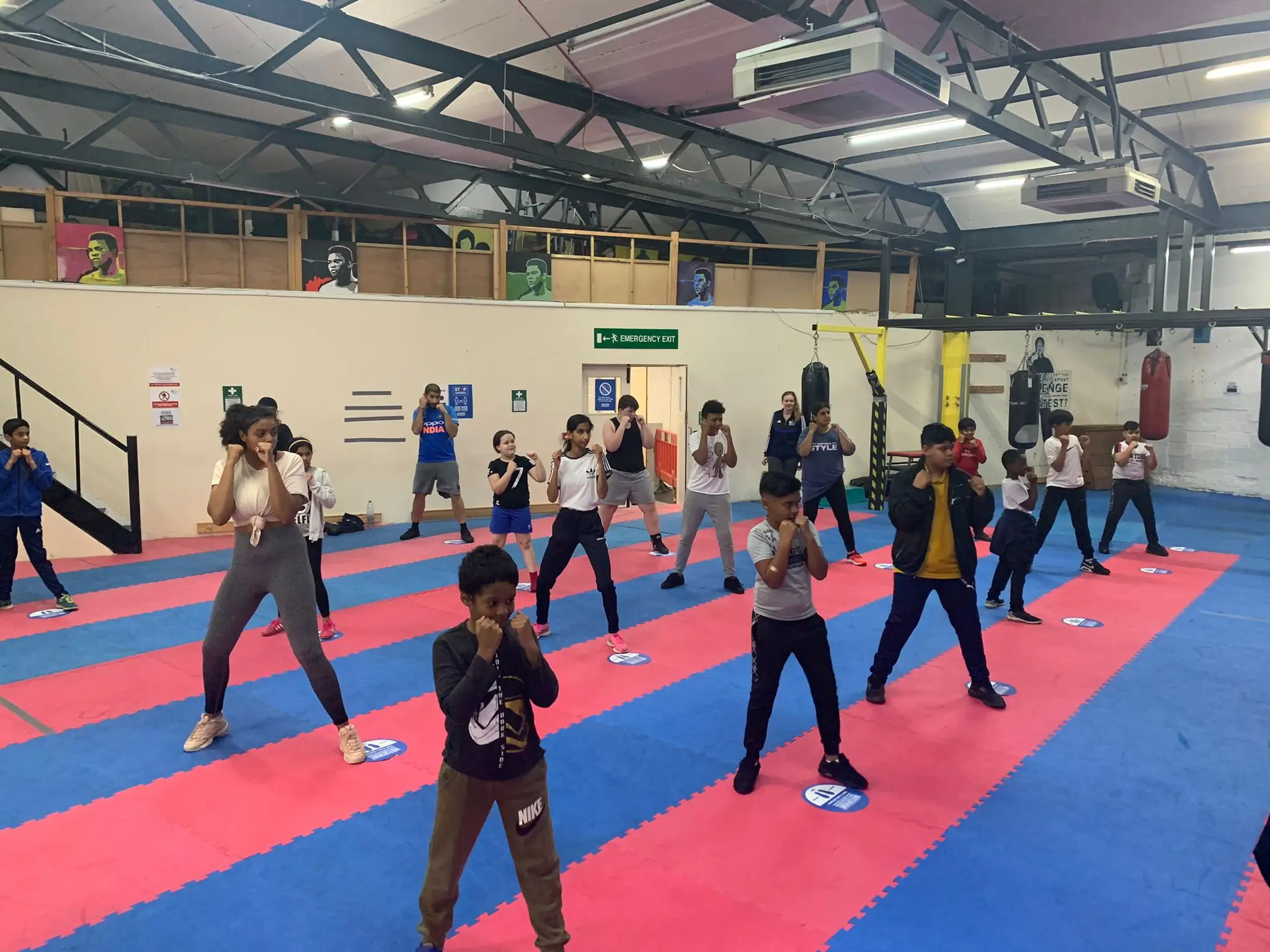 A large group of children and young people working through boxing stance drills together in the Waterfront gym