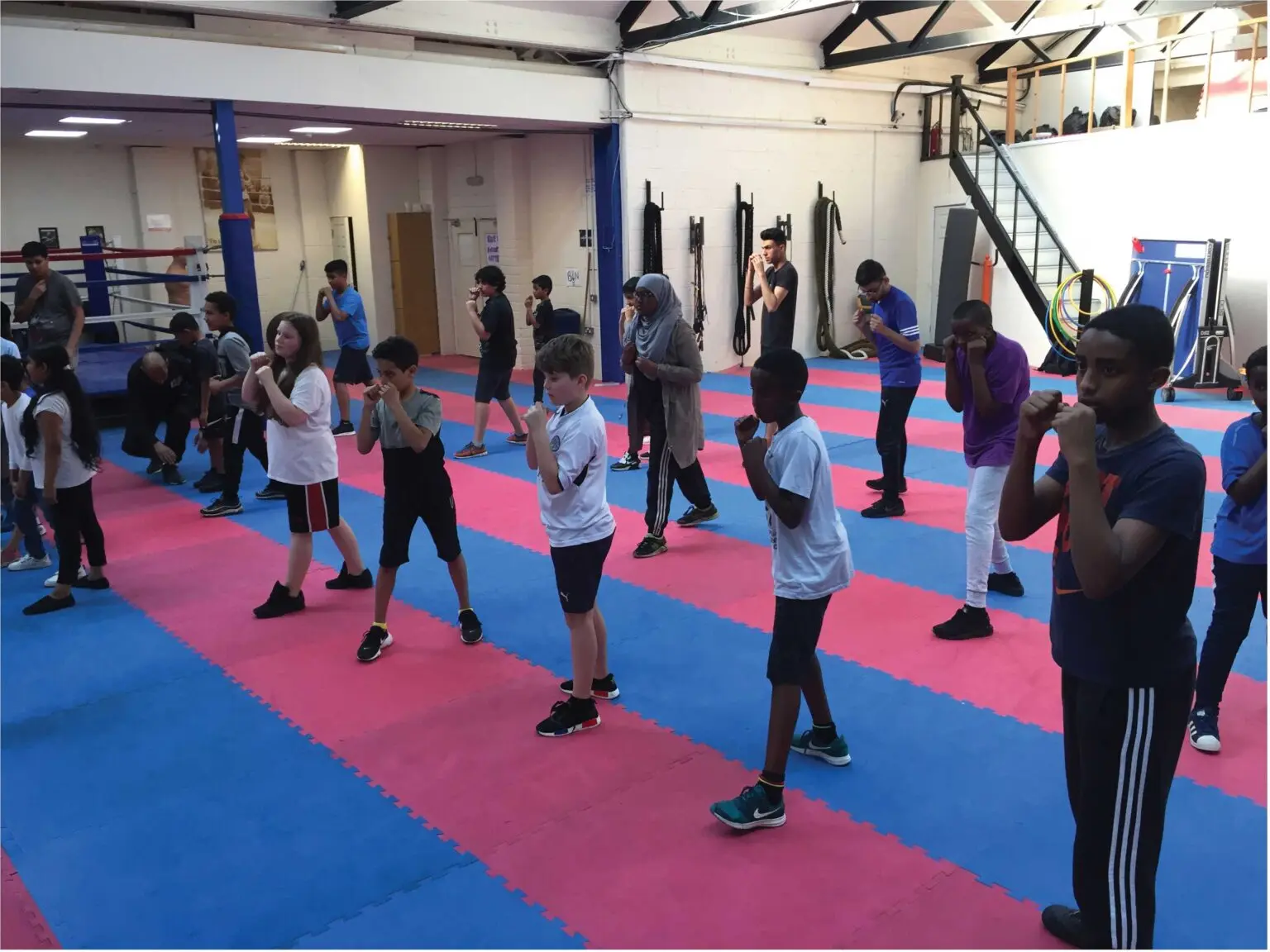 Young people working through boxing stance drills on the gym floor